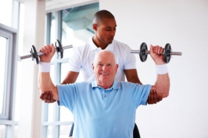 elder man doing physical therapy assisted by a caregiver