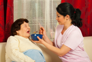 caregiver giving food to the elder woman